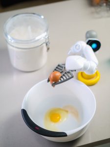 a robot cracks an egg into a bowl