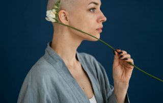 a woman holds a flower artistically against her head